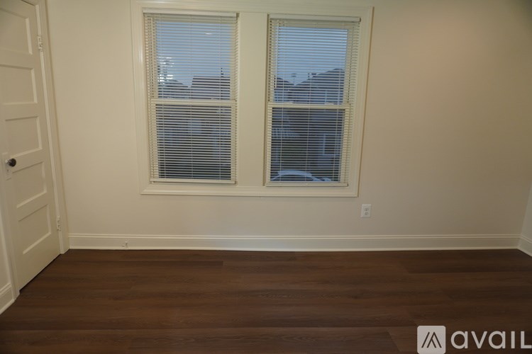 A room with two windows and wooden floors.