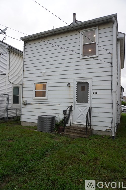 A white house with a black door and a window with a light on.