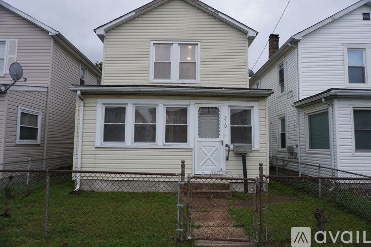 A house with a white door and windows is surrounded by a fence.