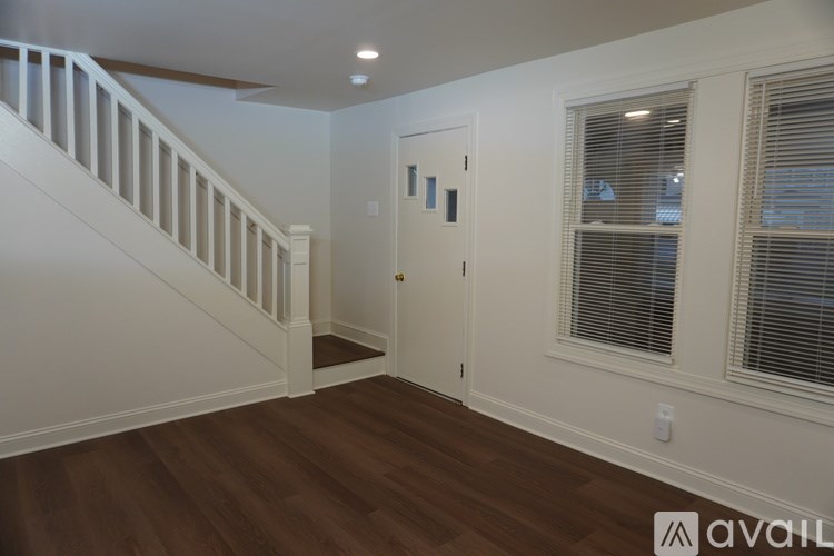 A room with a wooden floor and a staircase leading to the upper floor.