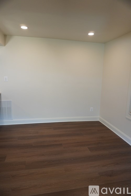 A room with wooden flooring and white walls.