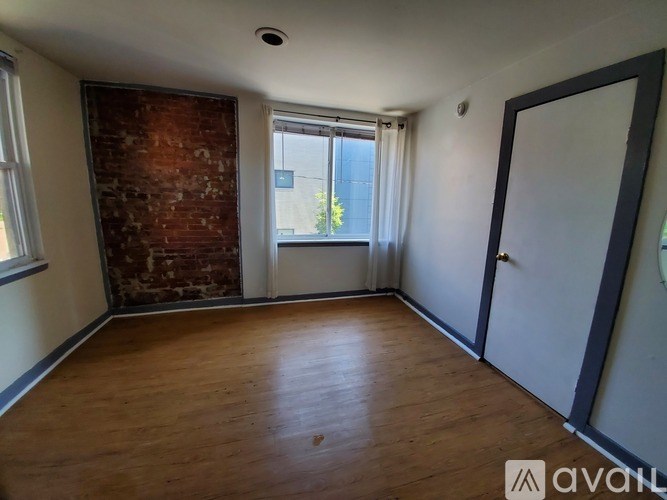 A room with a wooden floor and a brick wall.