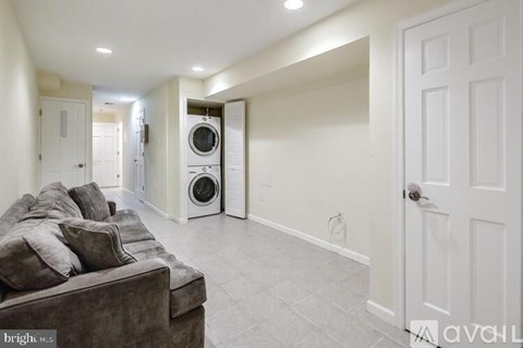 A living room with a couch and a washing machine in the background.