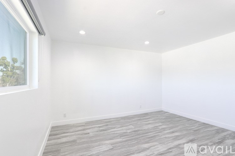 A room with a window and a wooden floor.