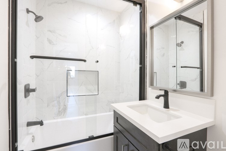 A modern bathroom with a marble wall and a black and white shower.