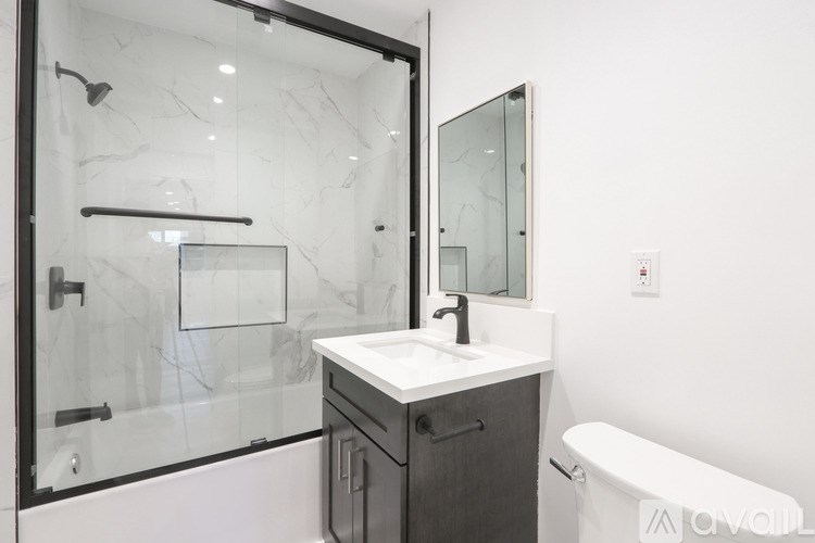 A bathroom with a marble shower and a white sink.