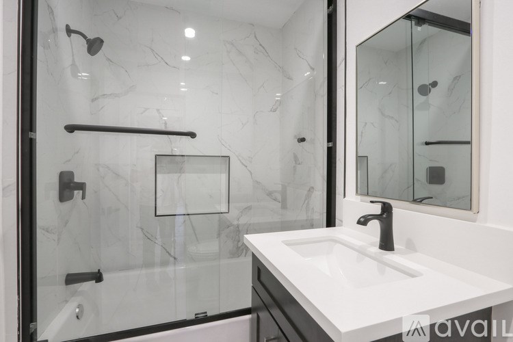 A modern bathroom with a marble shower and a white sink.