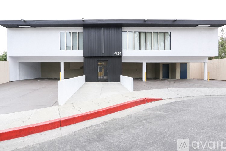 A modern building with a black and white facade and a red stripe around the edge of the driveway.