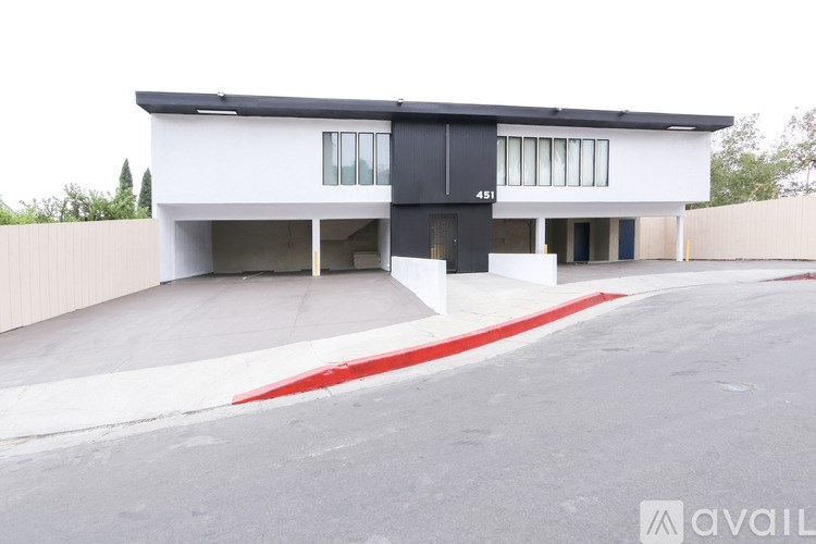 A modern house with a black and white exterior and a red stripe on the driveway.