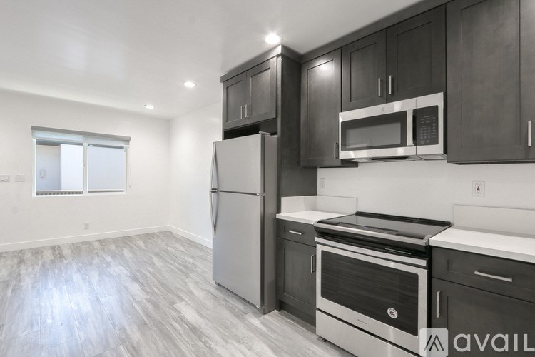 A kitchen with a refrigerator, oven, microwave, and cabinets.