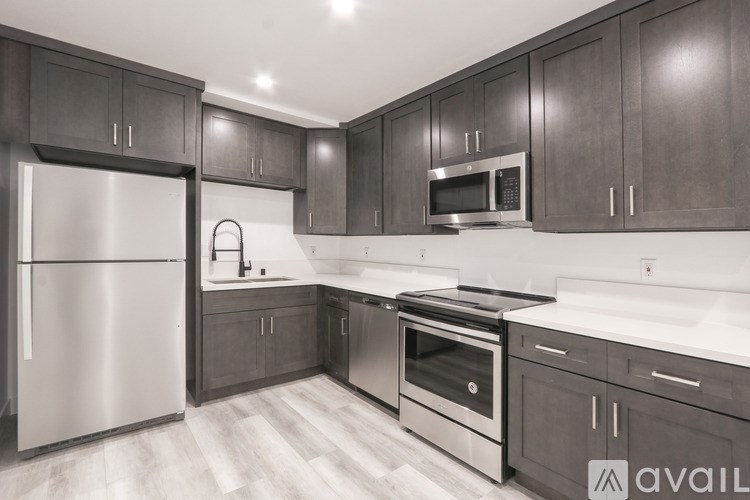 A modern kitchen with dark wood cabinets and stainless steel appliances.