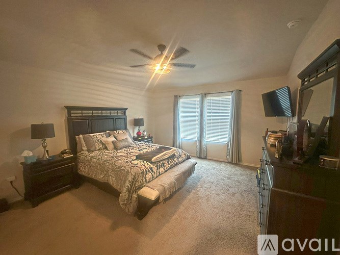 A bedroom with a large bed and a ceiling fan.