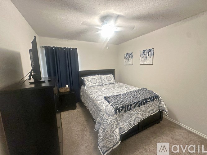 A bedroom with a bed, dresser, and a ceiling fan.