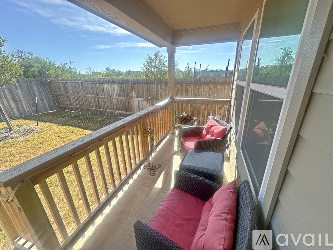 A balcony with a red cushion and a black chair.