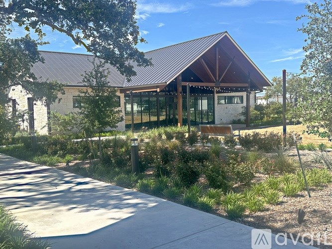 A modern building with a red roof and glass windows is surrounded by greenery.