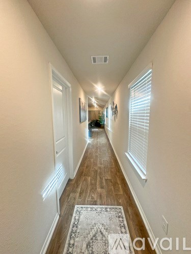 A long hallway with a rug on the floor and white walls.