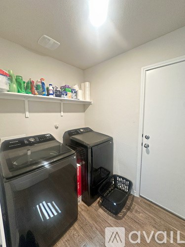 A kitchen with a black microwave, black oven, and a white door.