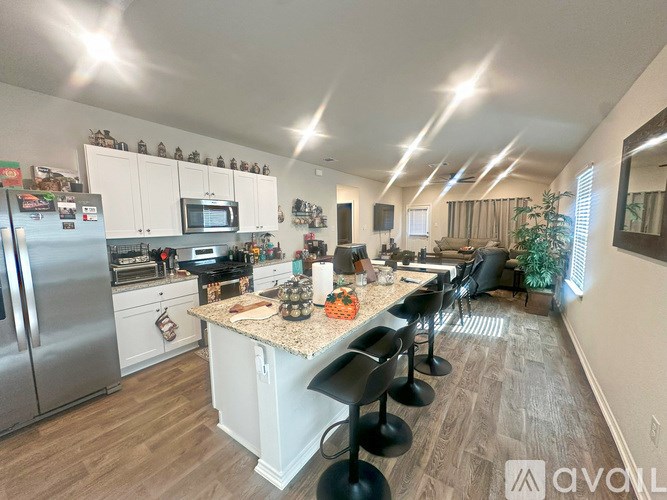 A well-lit kitchen with a granite countertop and stainless steel appliances.
