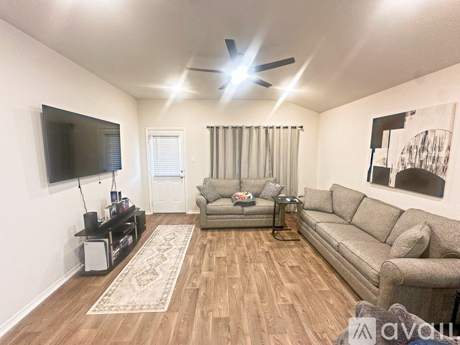 A living room with a grey couch, a television, and a rug.