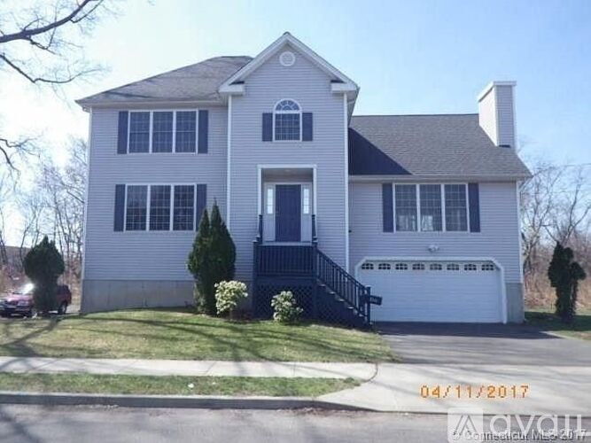 A white house with a black roof and a car parked in front.