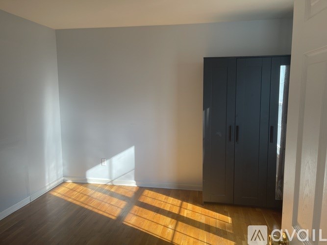 A white house with a black gate and a tree in front.