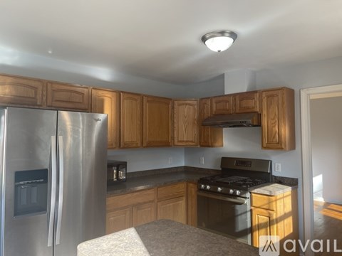 A kitchen with wooden cabinets and a stainless steel refrigerator.