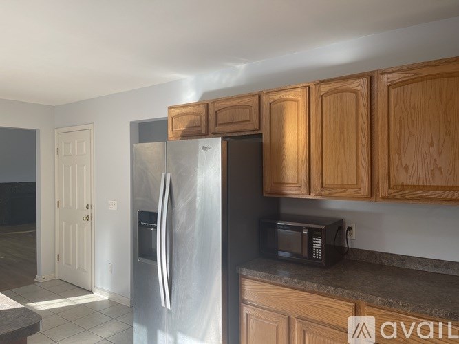 A kitchen with wooden cabinets and a stainless steel refrigerator.