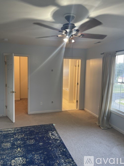 A room with a ceiling fan and a rug on the floor.