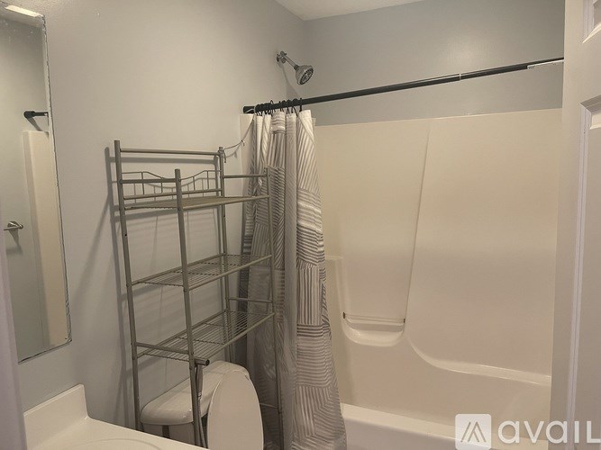 A bathroom with a toilet, a shower with a curtain, and a towel rack.