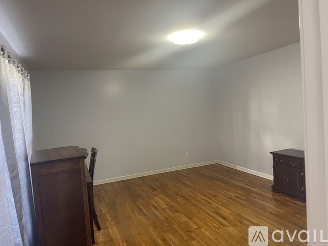 A room with wooden flooring and a wooden cabinet.