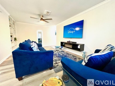 A living room with blue chairs and a Disney+ logo on the wall.