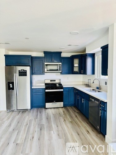 A kitchen with blue cabinets and a white refrigerator.