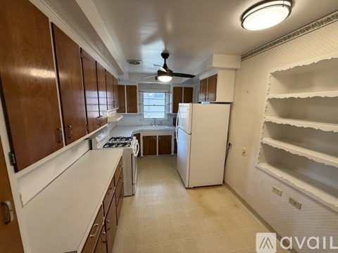 A kitchen with brown cabinets and a white refrigerator.