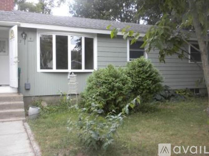 A small house with a grey front yard and a white door.