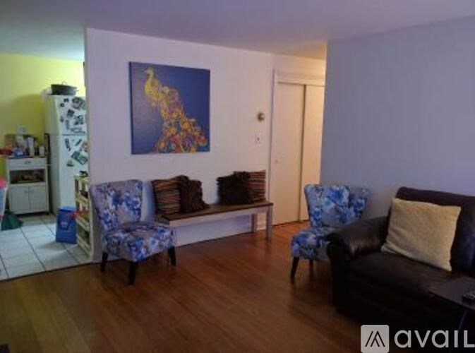 A living room with a couch, two chairs, and a painting on the wall.