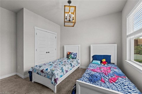 A bedroom with two beds and a chandelier.