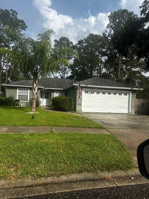 A house with a garage and a tree in front.
