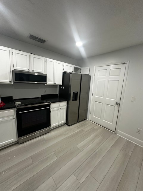 A kitchen with white cabinets and a refrigerator.