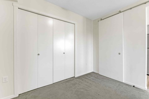 A room with white cupboards and grey carpet.