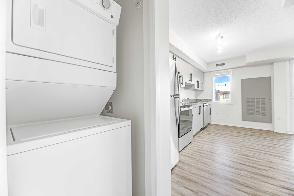 A white washing machine in a kitchen with wooden flooring.
