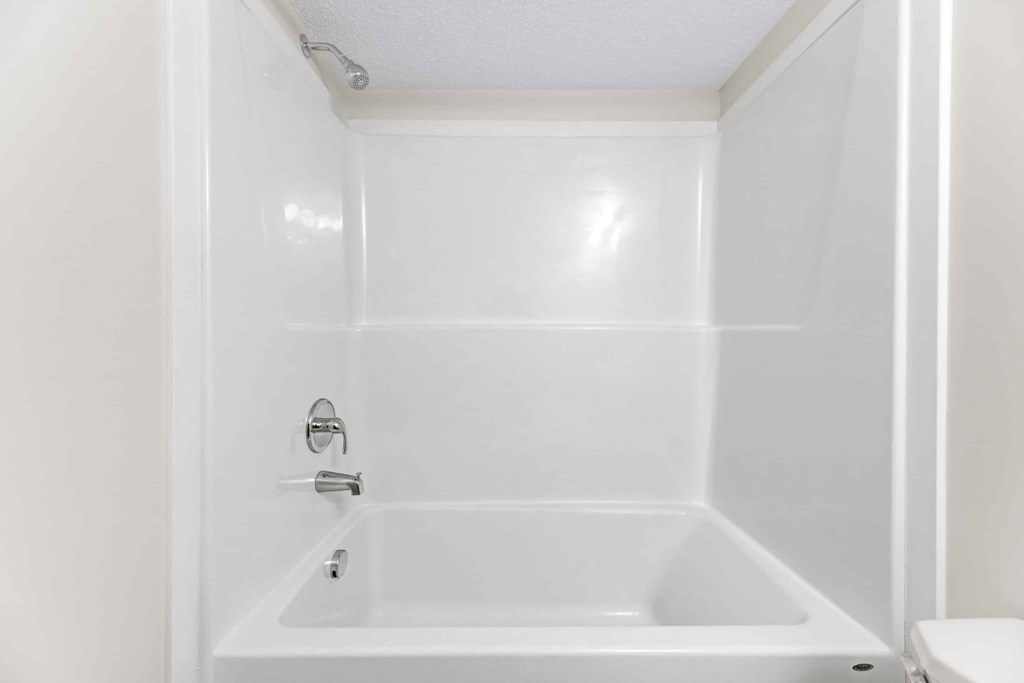 A white bathroom with a tub and toilet.