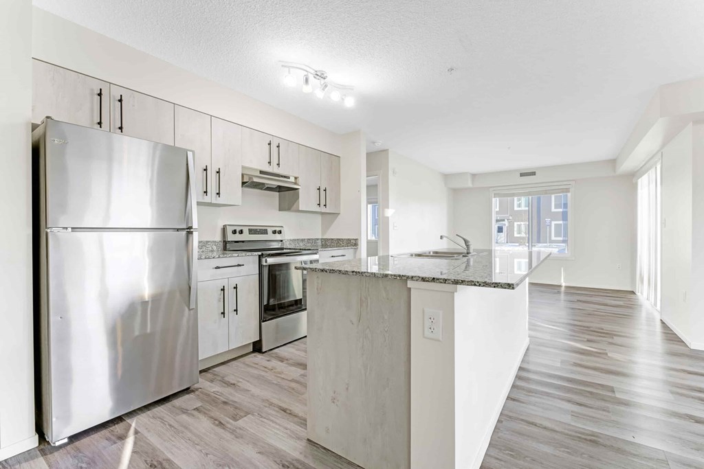 A kitchen with a refrigerator, microwave, oven, and sink.