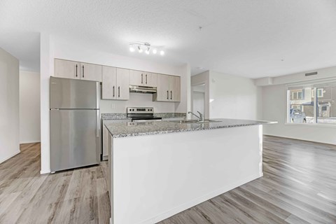 A modern kitchen with a stainless steel refrigerator and a white island.