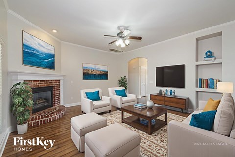 A living room with a fireplace and a painting of a beach scene on the wall.