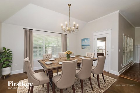 A dining room with a table set for four and a chandelier hanging from the ceiling.