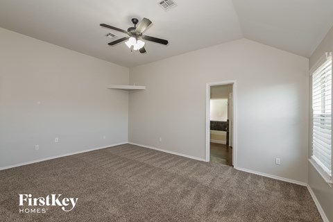 A spacious room with a carpeted floor and a ceiling fan.