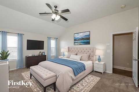 A bedroom with a large bed, a ceiling fan, and a painting on the wall.