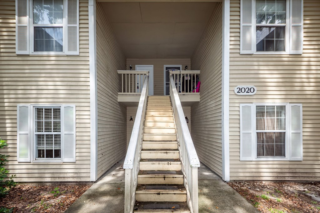 A staircase leads to a balcony on the second floor of a house.