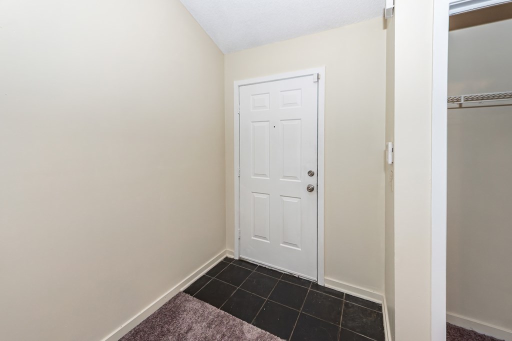 A white door is in a room with a purple rug on the floor.