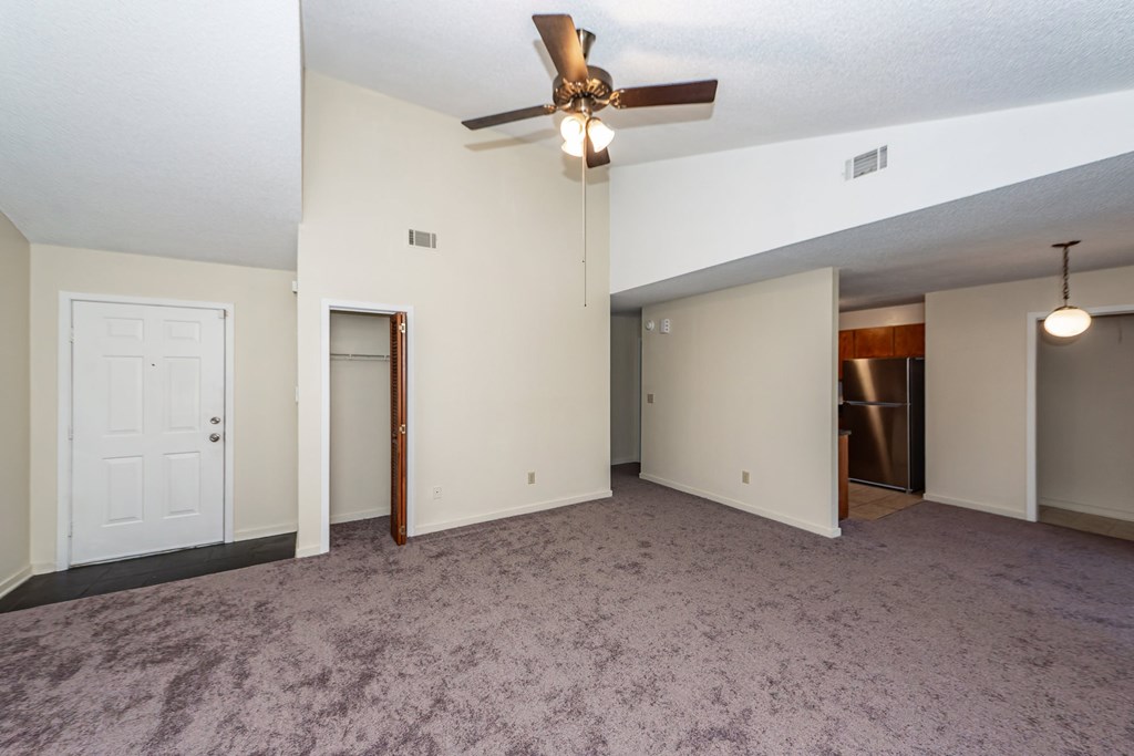 A room with a ceiling fan and carpeted floor.